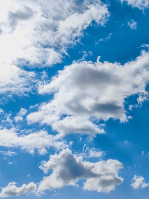 Free Bright blue sky filled with fluffy white clouds, perfect for nature backgrounds. Stock Photo