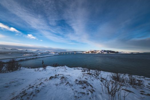 A picturesque winter view of the Atlantic Ocean Road bridge surrounded by snowy landscapes in Norway.