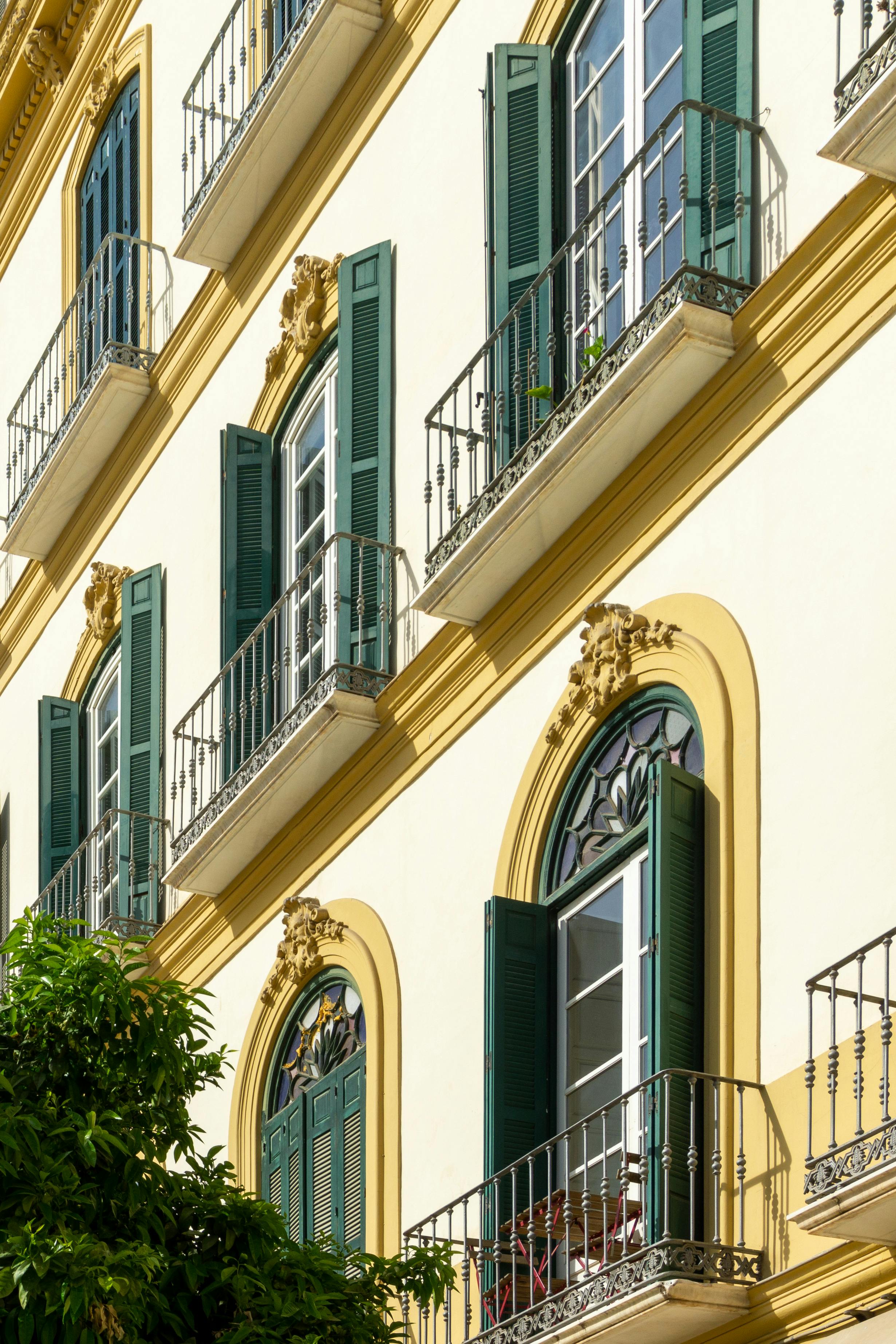 Captivating view of a traditional Andalusian facade in Málaga, showcasing ornate architecture and green window shutters.