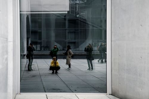 Free A group of people reflected in an urban building's glass facade, showcasing modern architecture and street life. Stock Photo