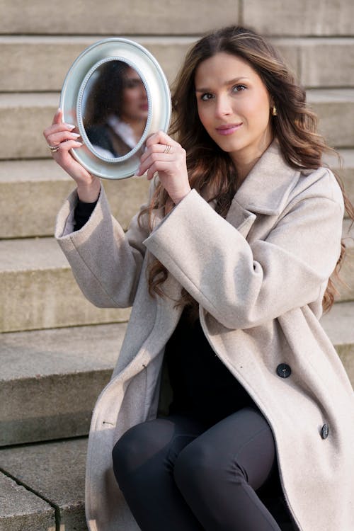 A woman sitting on steps holding a mirror