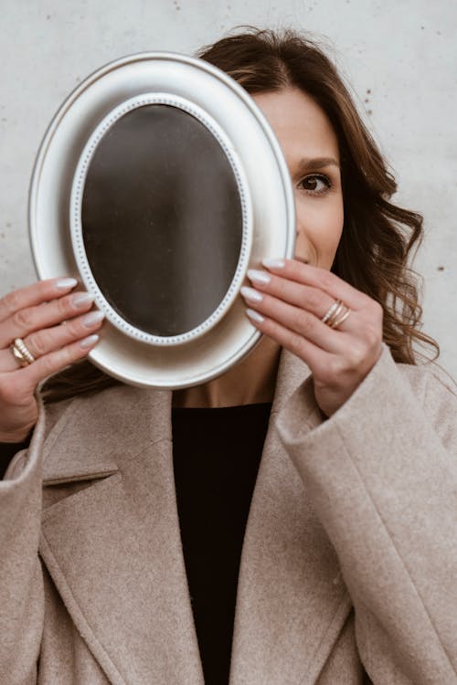 A woman holding a mirror in front of her face