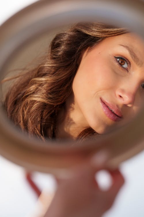 A woman looking in a mirror at her face
