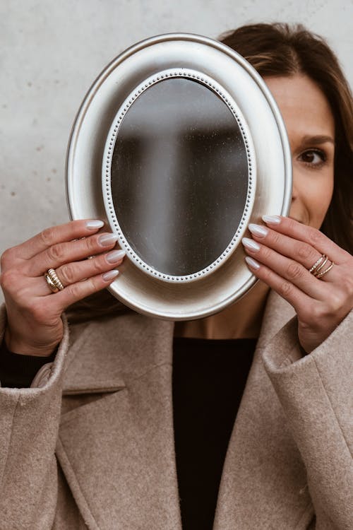 A woman holding up a mirror with a ring on it