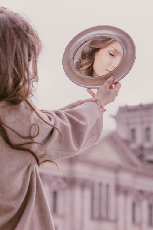 A woman is looking at her reflection in a mirror