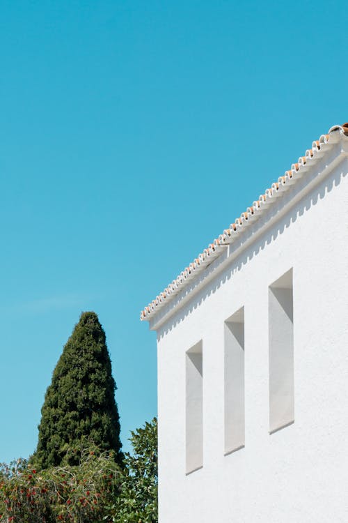 A white building with a blue sky and trees