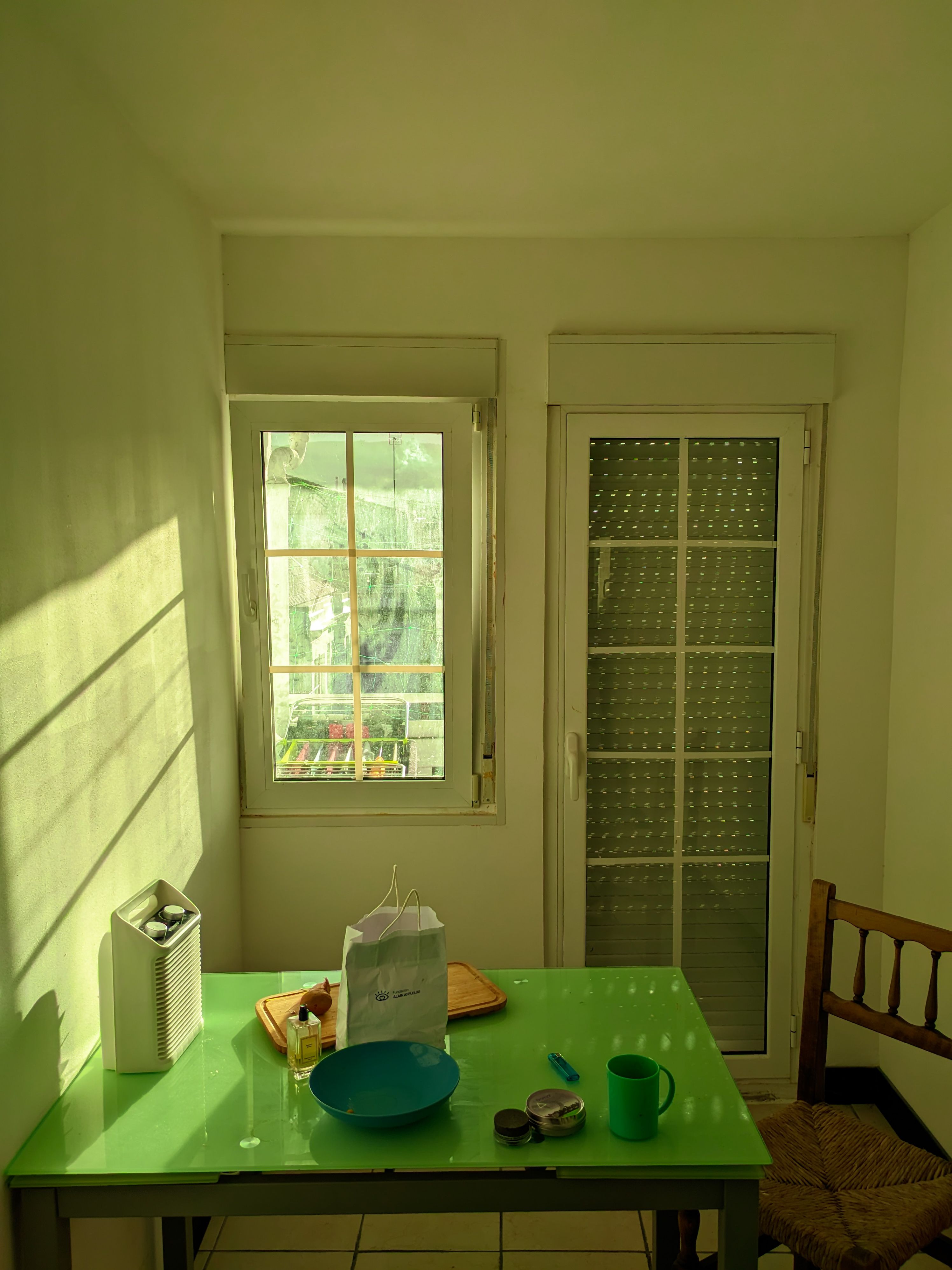Cozy kitchen corner with green table and sunlight streaming through windows, creating a warm ambiance.