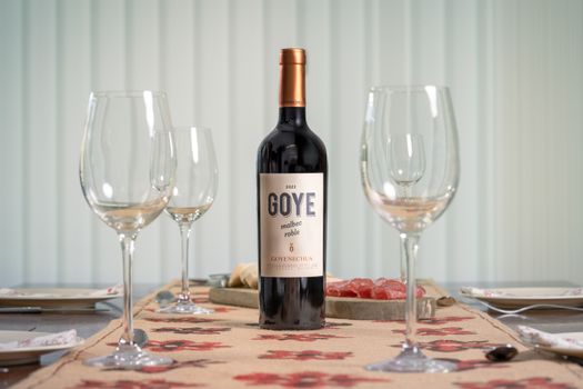 A bottle of Goye Goyenechea Malbec wine elegantly placed with empty glasses on a table, ready for a celebration.