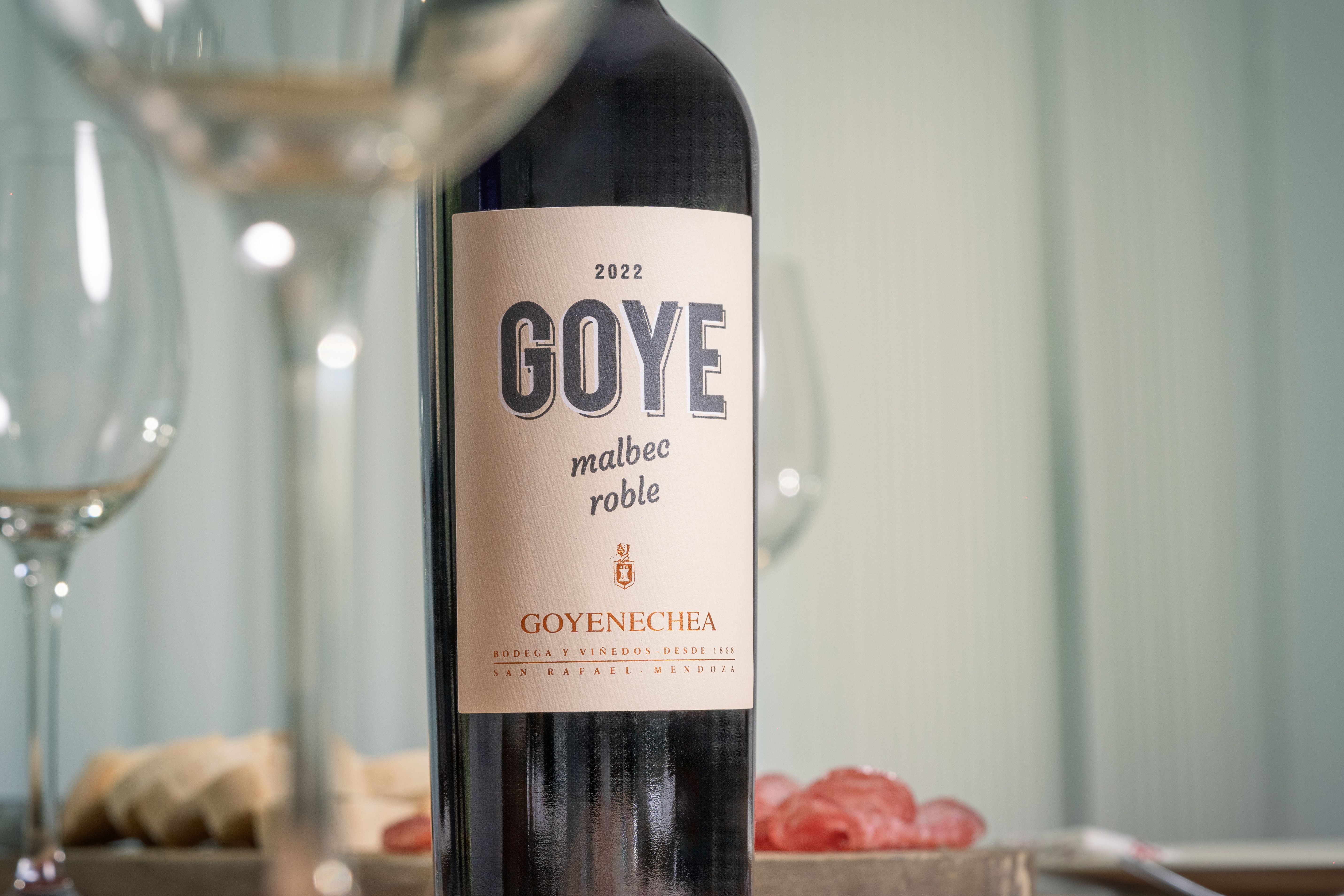 Elegant Goye Malbec wine bottle on a table with wine glasses and snacks.