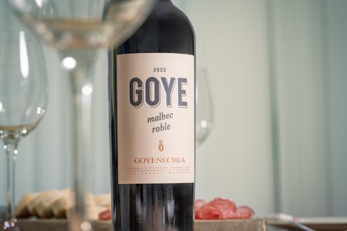 A bottle of goye wine sits on a table next to a glass of wine