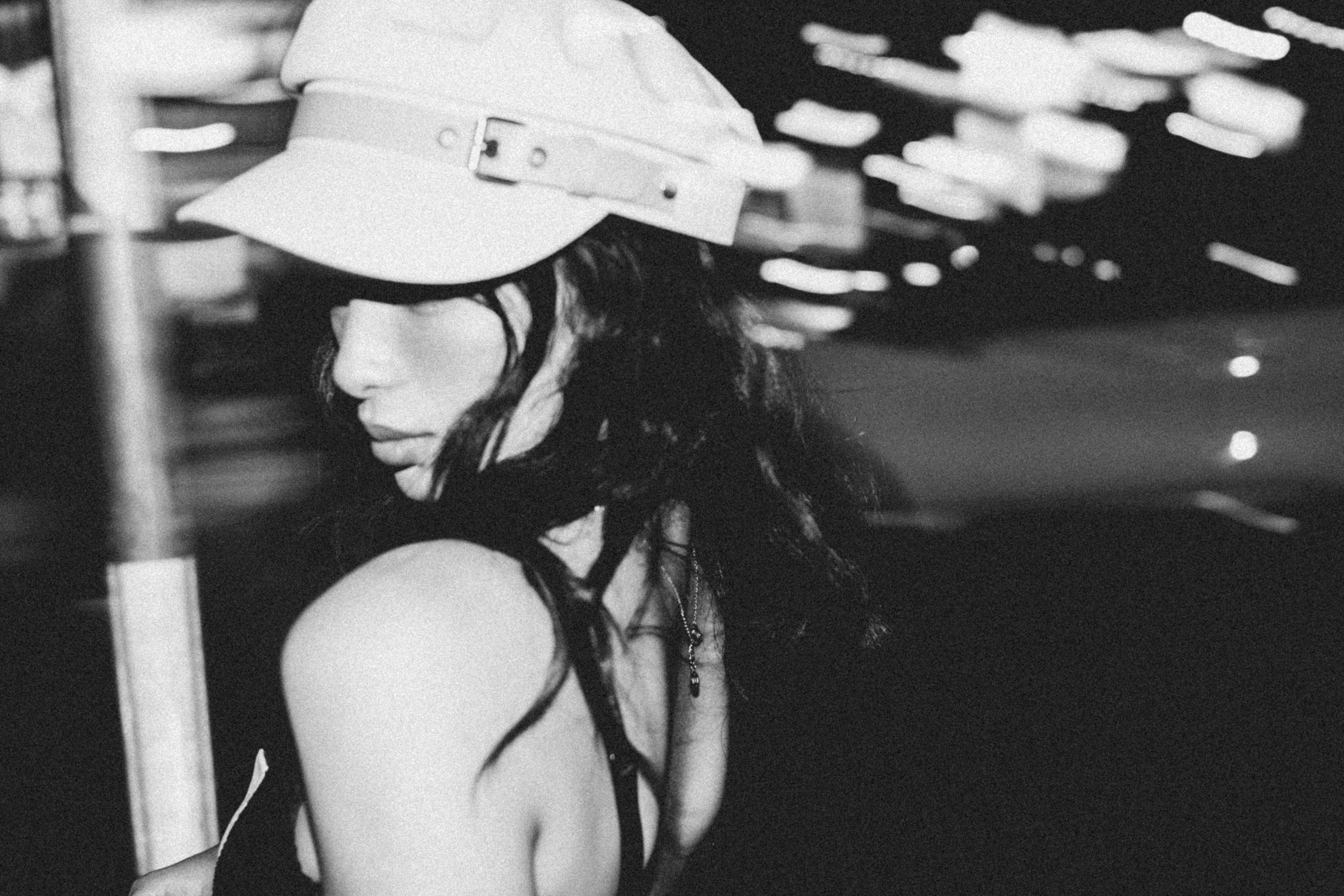 Artistic black and white photo of a woman posing in an urban setting at night.
