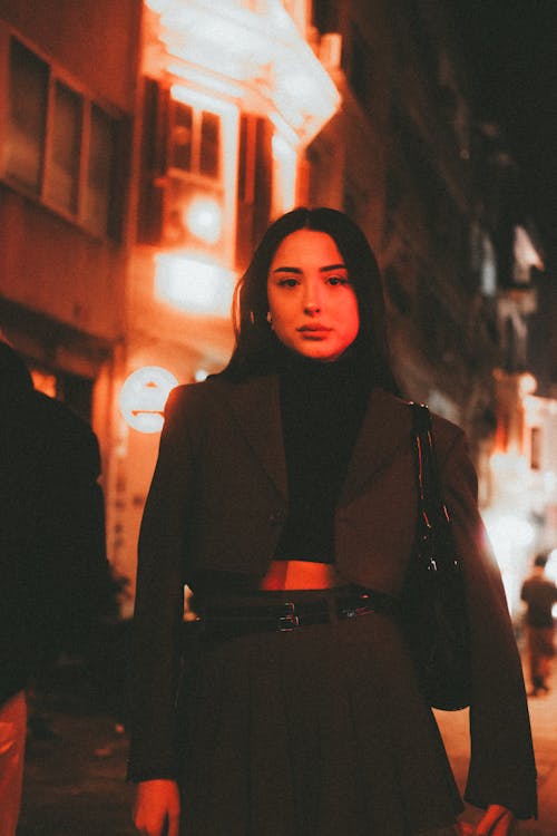 A woman in a skirt and jacket standing in the street