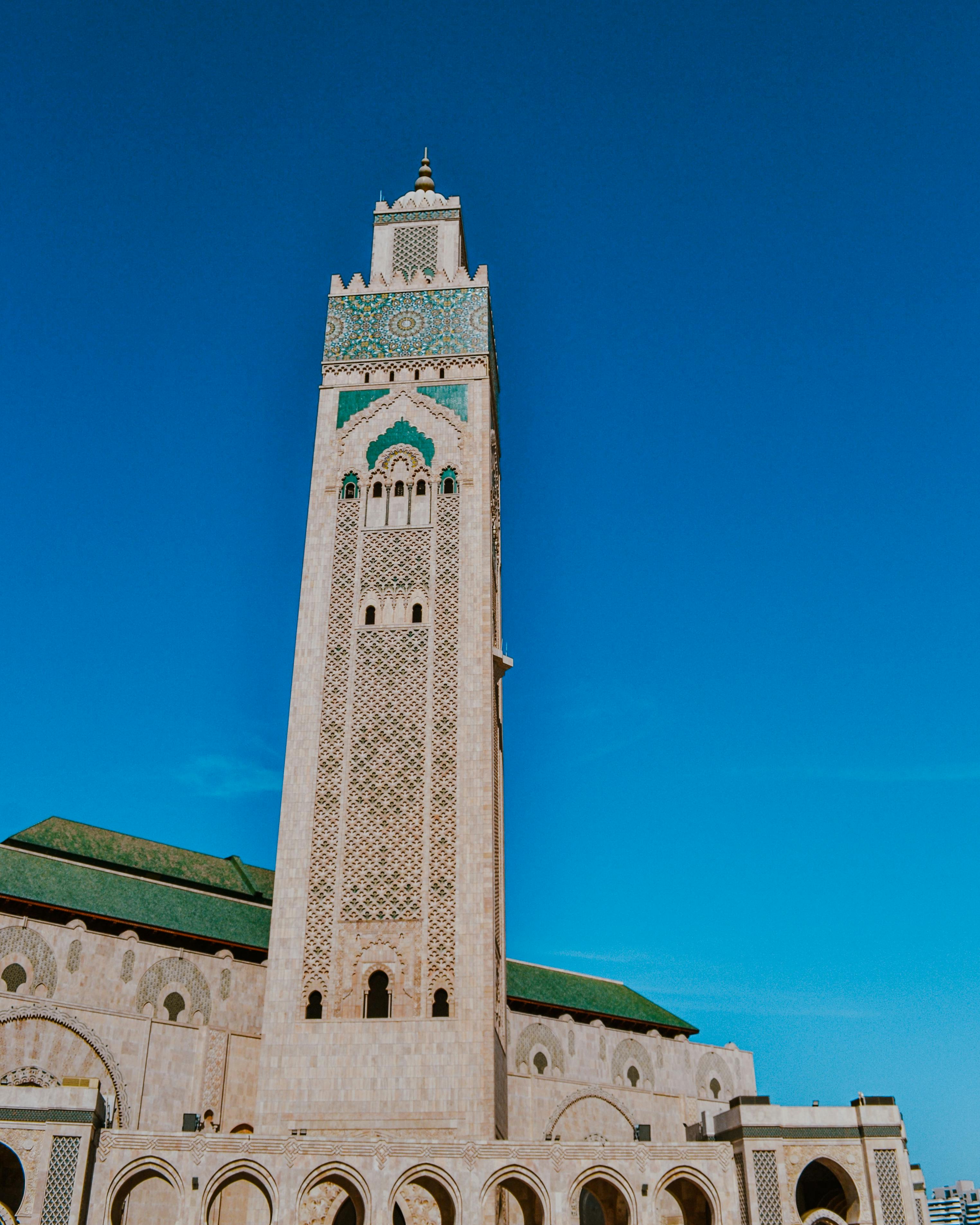 A stunning view of the towering Hassan II Mosque in Casablanca, Morocco, with a clear blue sky.