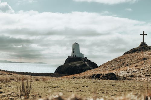 A cross and a lighthouse on a hillside