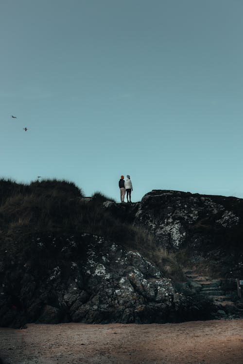 Couple Standing on Rocks Hill on Coast