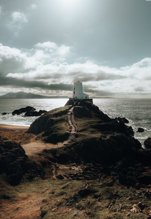 A lighthouse on the coast with a cloudy sky