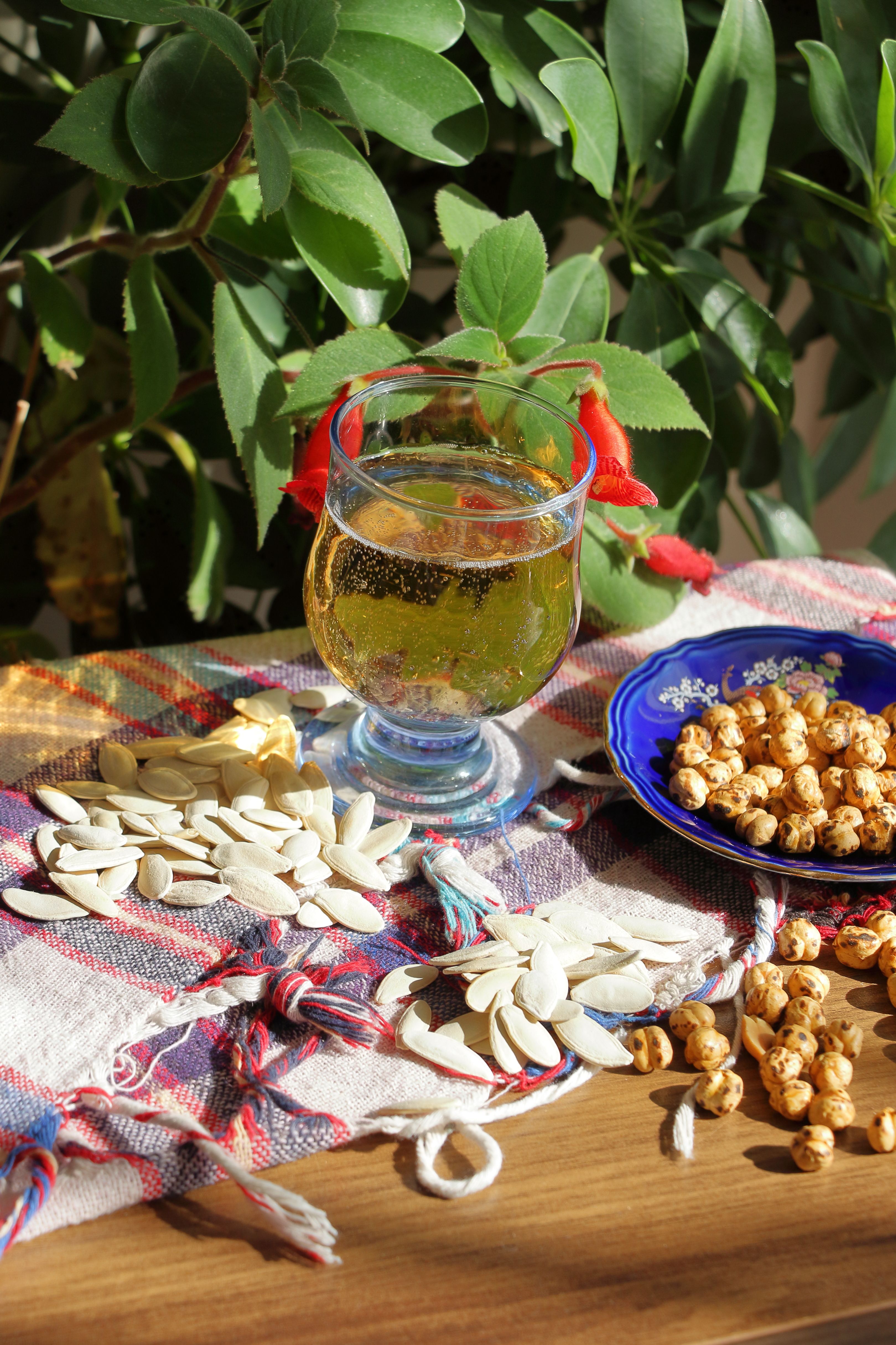 Refreshing drink with assorted nuts on a plaid tablecloth, perfect for a cozy snack time.