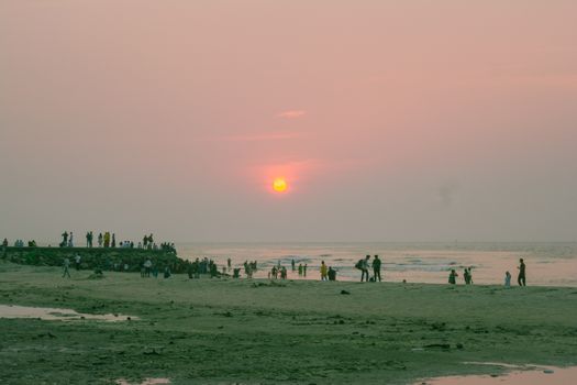 A tranquil sunset scene on a beach with people relaxing by the sea, perfect for travel and lifestyle themes.