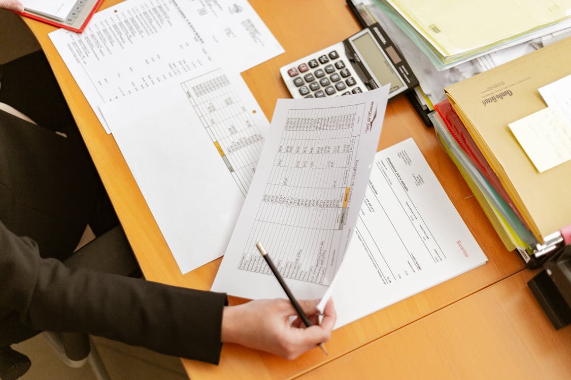 Person Holding White Printer Paper and Pen