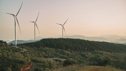 Wind turbines on a hillside with a sunset in the background