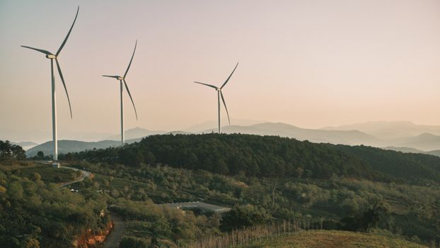 Wind turbines on a hilly rural landscape during dusk, promoting green energy.