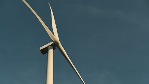 A wind turbine is shown against a blue sky