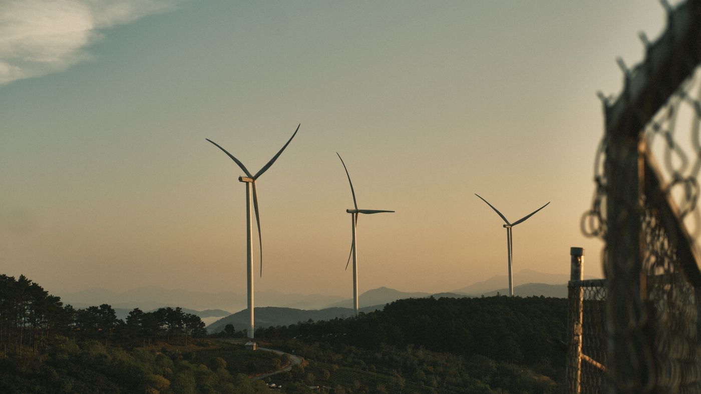 Scenic view of wind turbines on a hillside at sunset, symbolizing renewable energy.