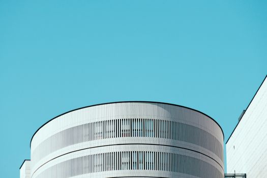 Minimalist white modern building with a clear blue sky backdrop, showcasing contemporary architectural design.