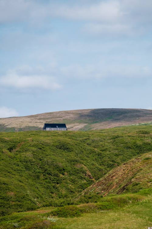 A small house on a hillside with a green grassy hill