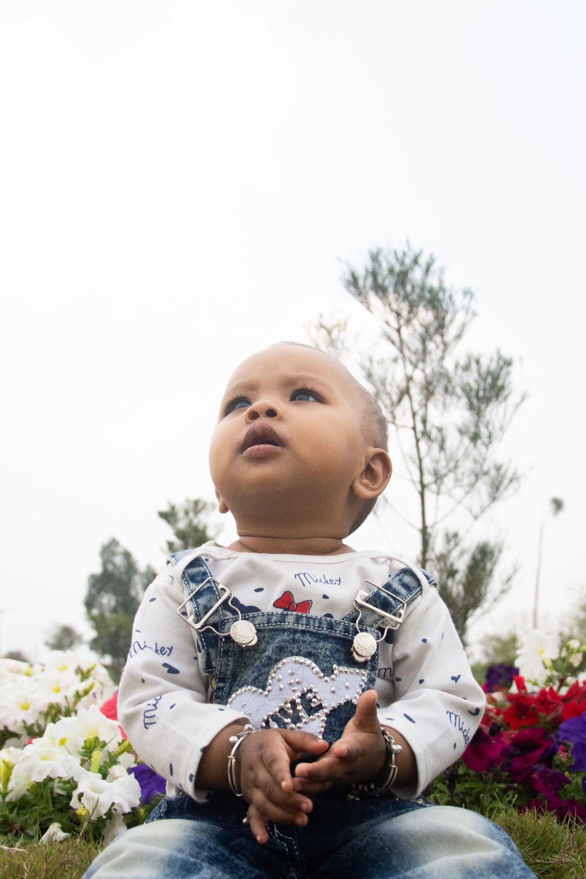 Baby girl in denim overalls with flowers