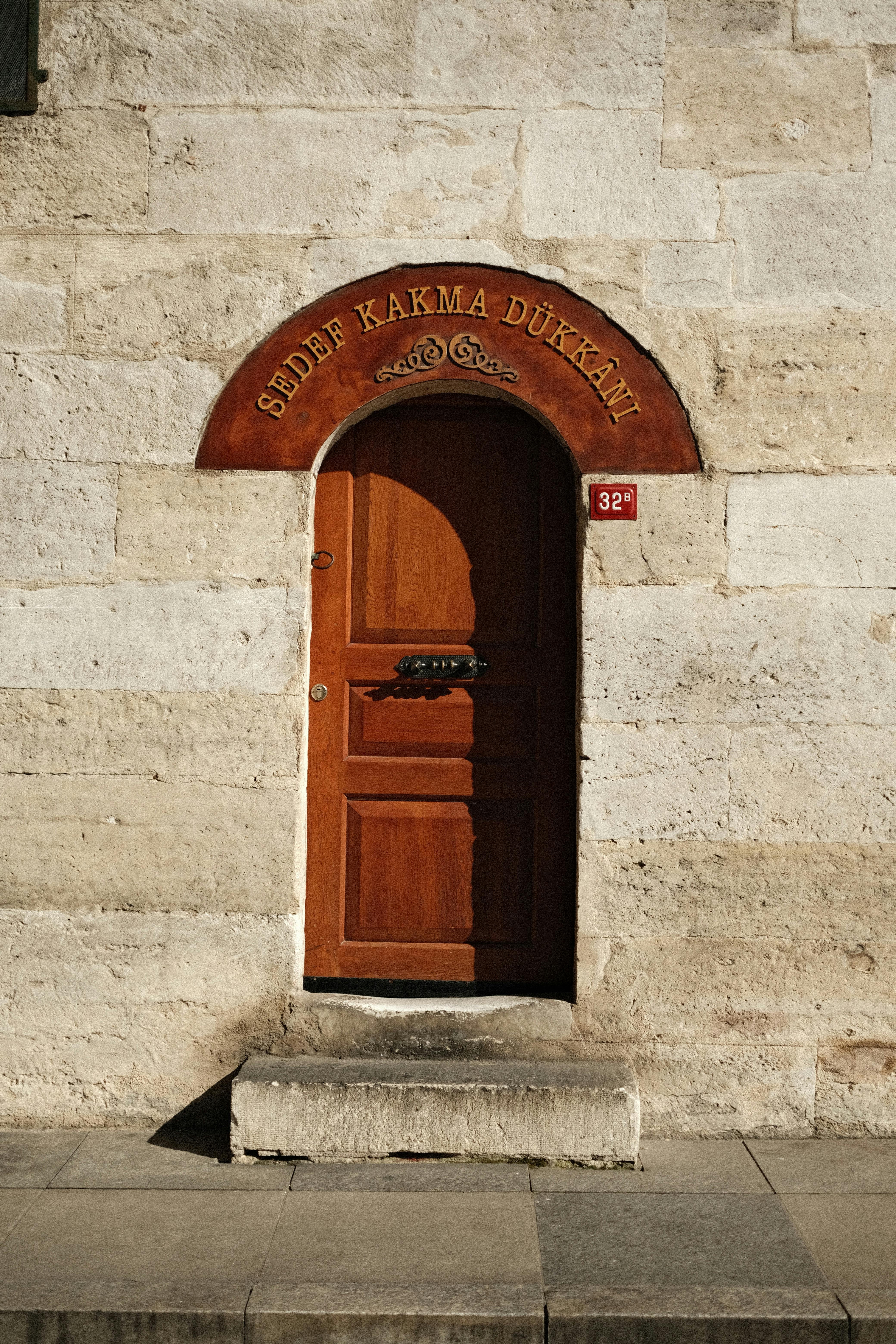 A rustic stone building featuring a classic wooden door with ornate signage above.