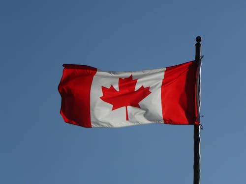 Canadian Flag against the Backdrop of Clear Blue Sky 