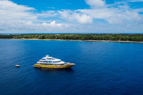 Free Aerial view of a luxury yacht cruising near Fuvahmulah, Maldives against a lush island backdrop. Stock Photo