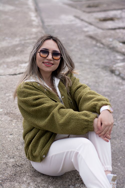 Blonde Woman Sitting in Sunglasses and Green Jacket