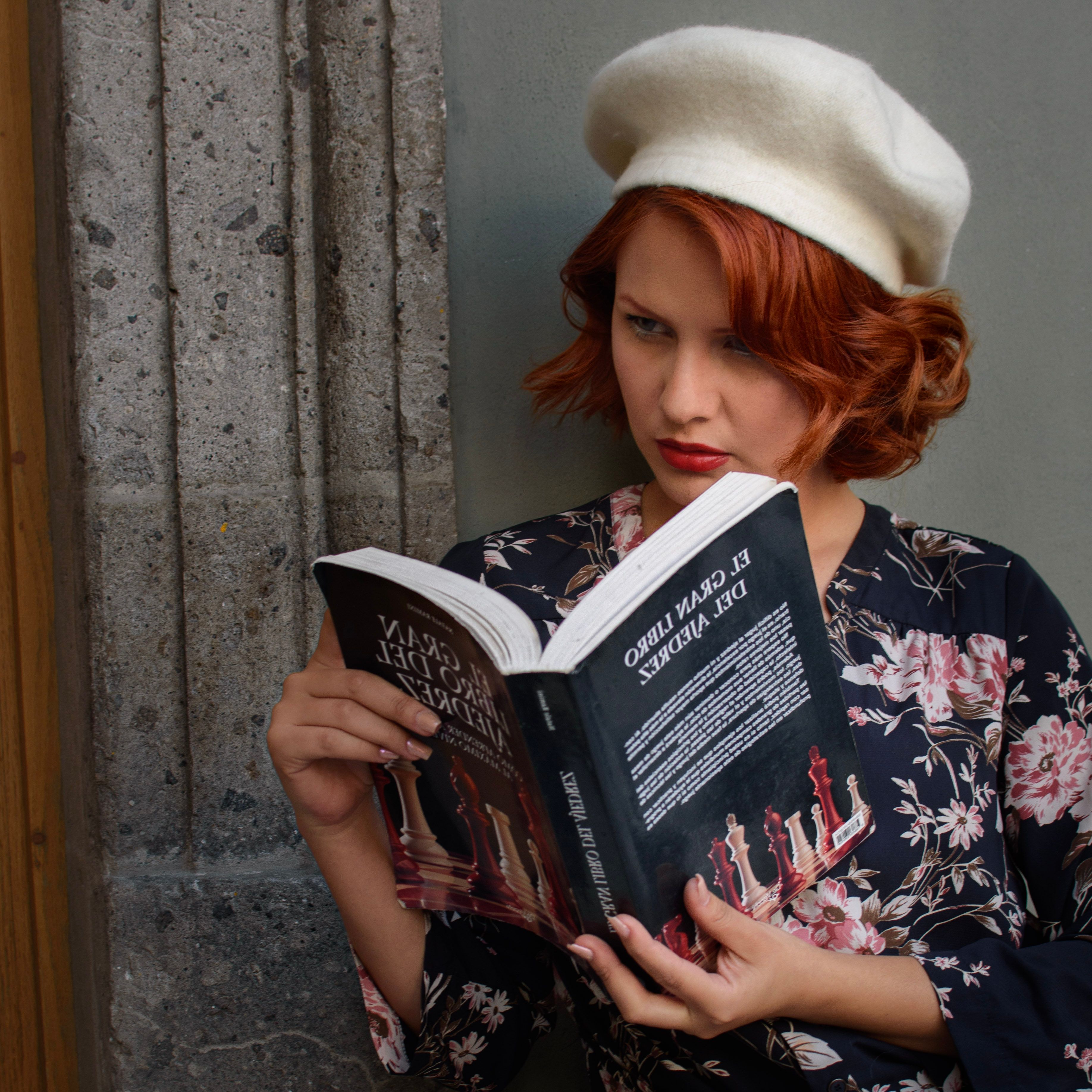 Woman wearing a beret and floral dress, reading a book outdoors in Ciudad de México.