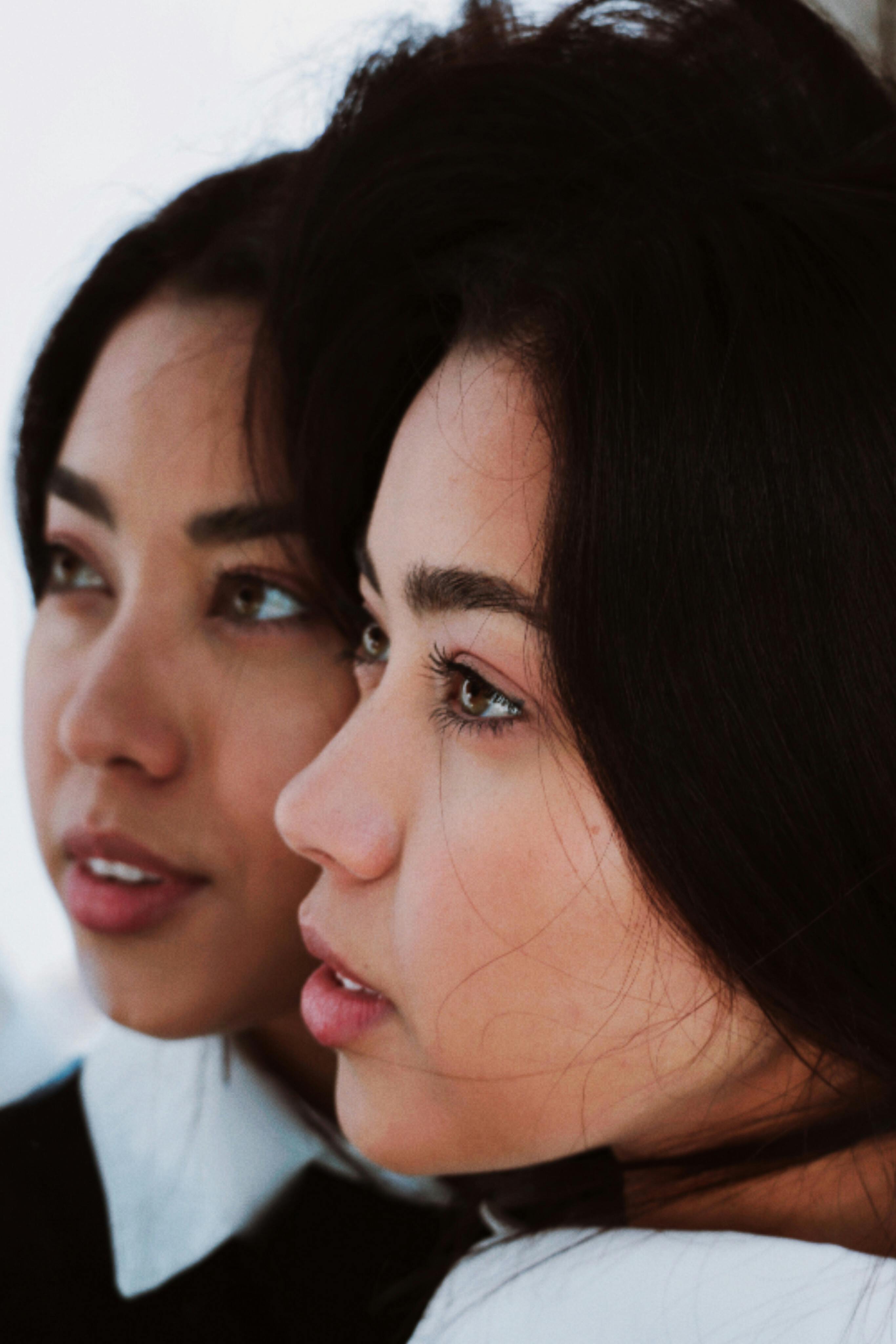 Intimate close-up portrait of two women with black hair looking thoughtful. Captured in Berlin, Germany.