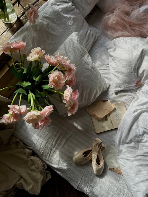 Pink Flowers on Bed with Pillows and Shoes