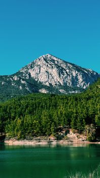 Scenic view of a mountain and pine trees at Doyran Lake, Antalya, Türkiye.