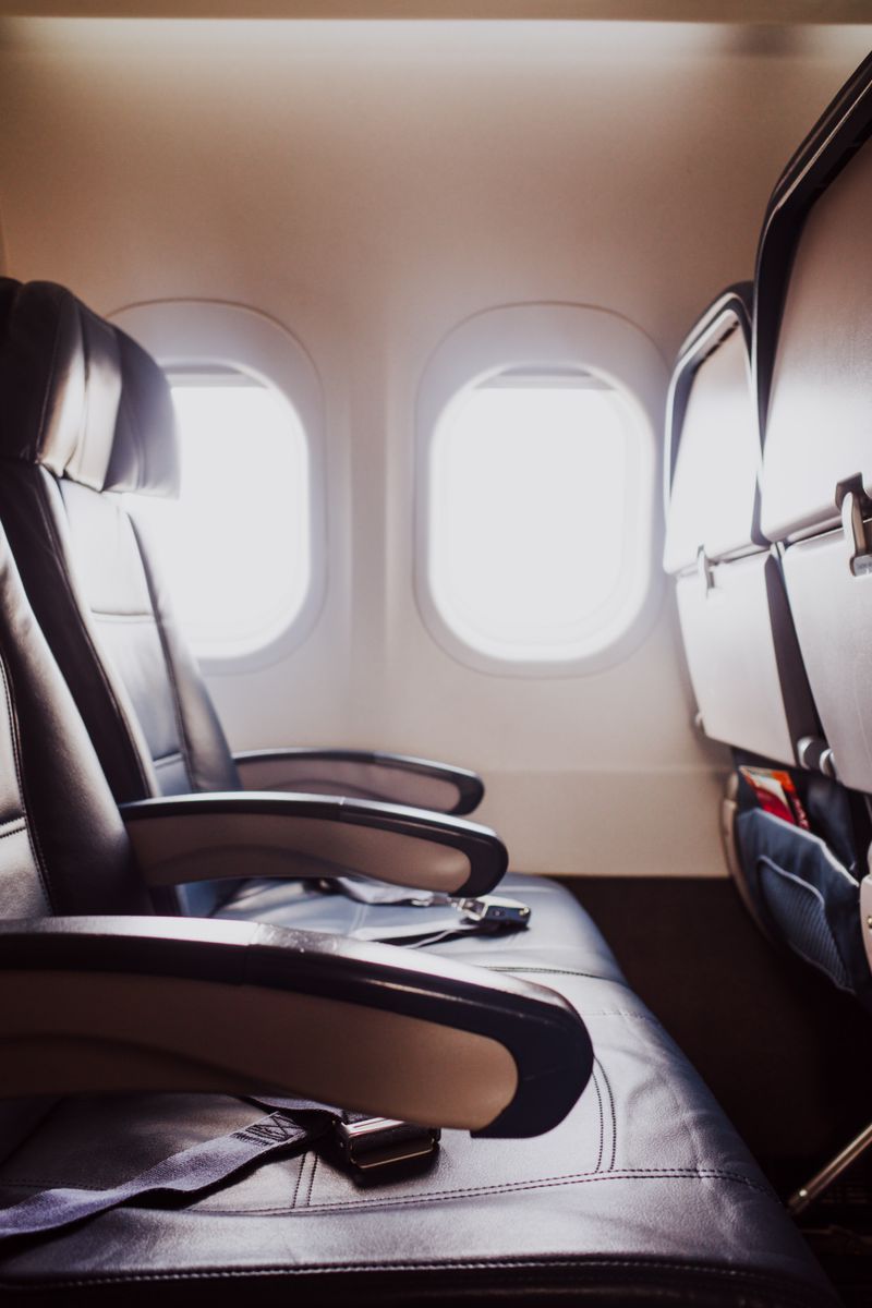 Empty leather aircraft seats beside cabin windows