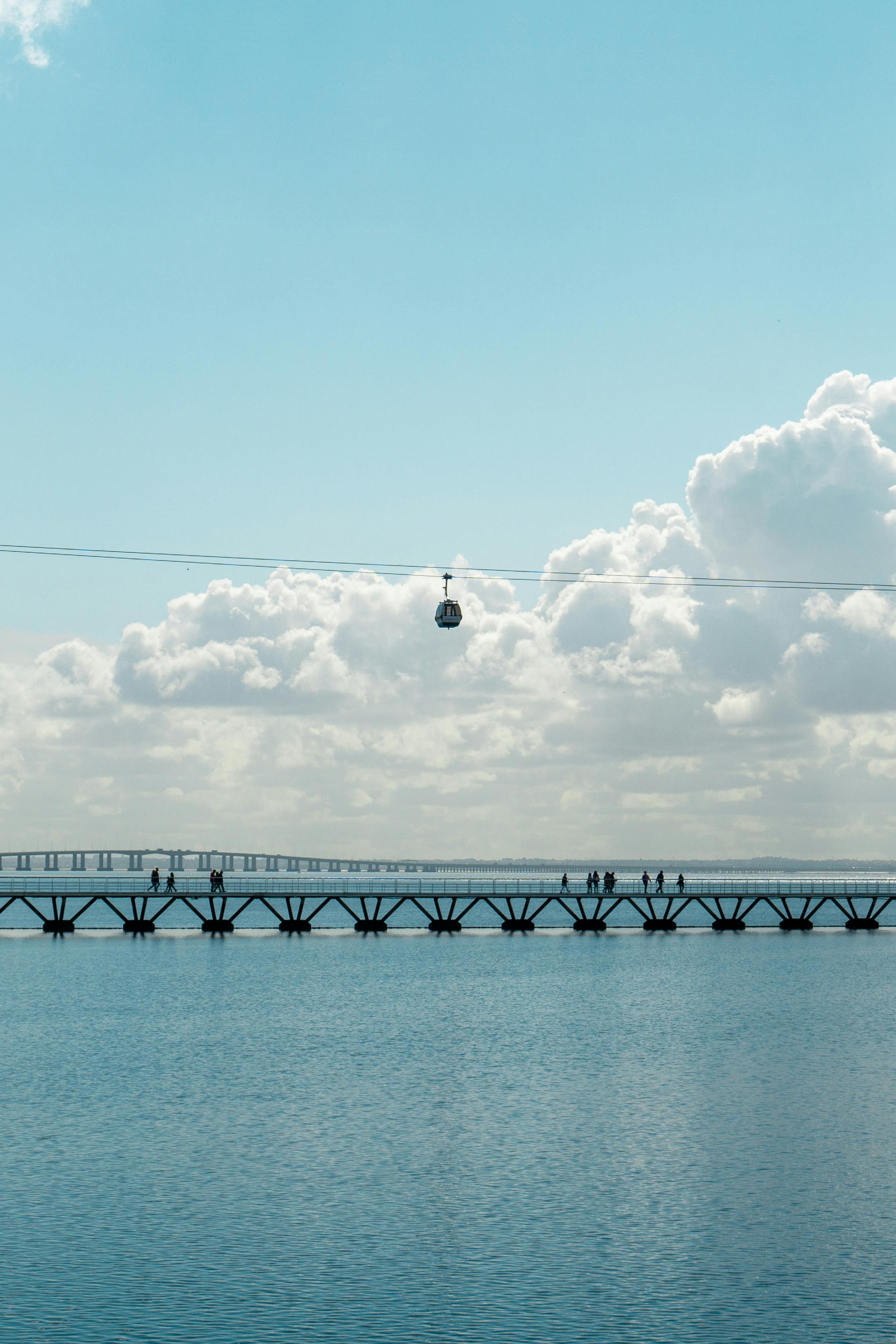 Gondola lift over the waterfront in Lisbon with a blue sky and clouds.