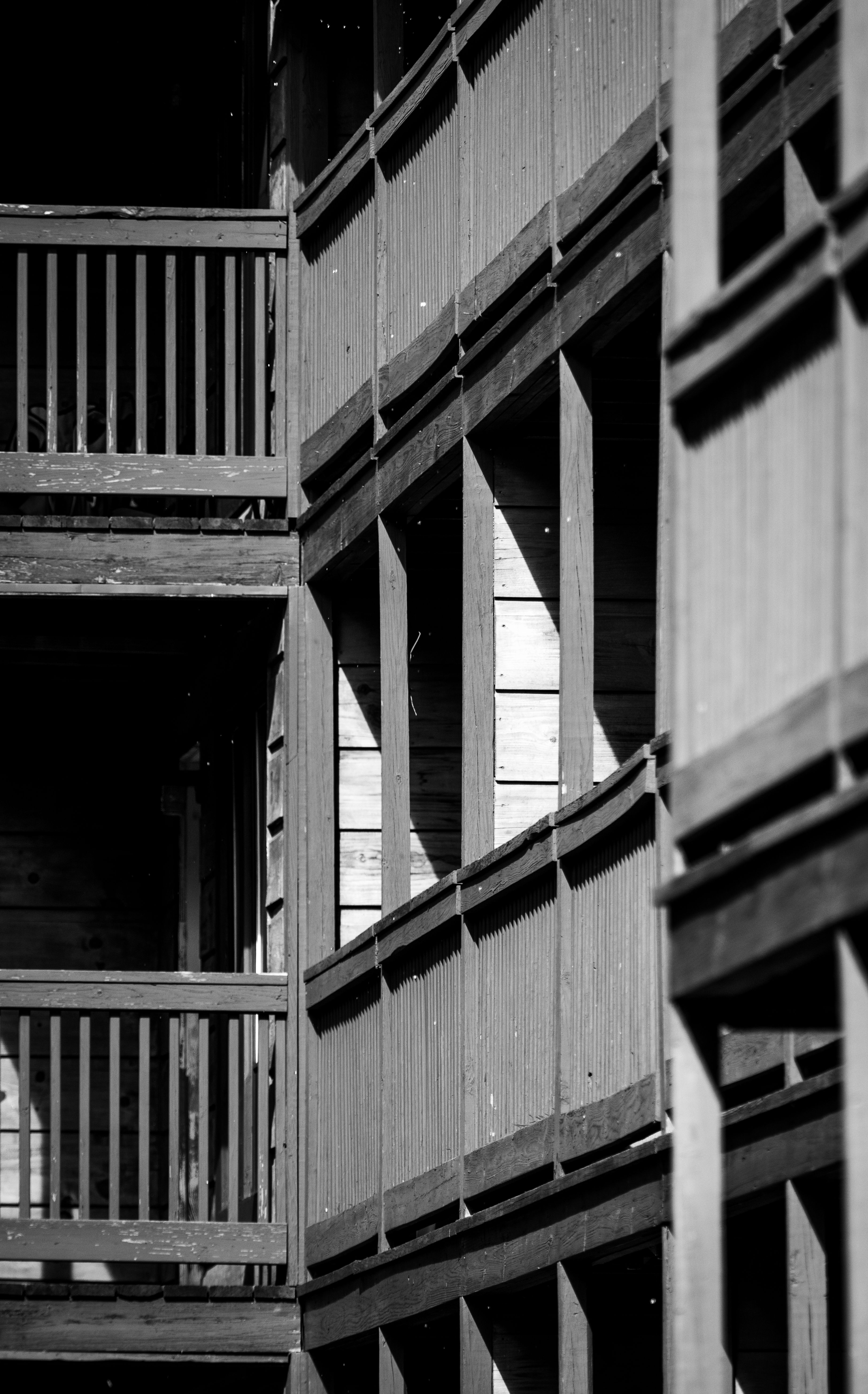 Black and white photo of an urban building with vertical wooden panels and railings.