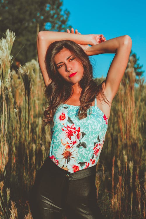 Free Woman In Teal And Red Floral Top Standing On Grass Field Stock Photo