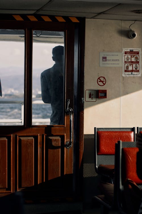 A man is looking out the window of a boat