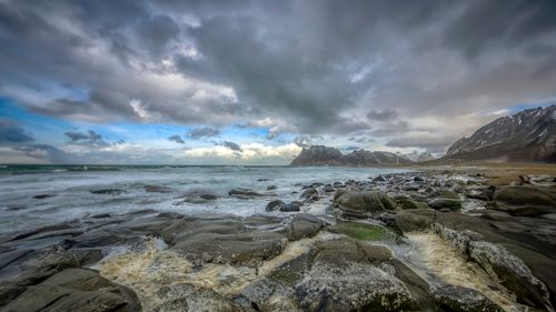 Free Breathtaking view of a wintry coastal landscape with rugged rocks and snowy mountains. Stock Photo