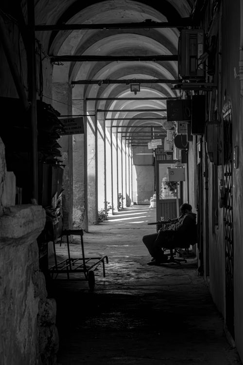 Free Monochrome alley scene in Istanbul with a man sitting under arches. Stock Photo