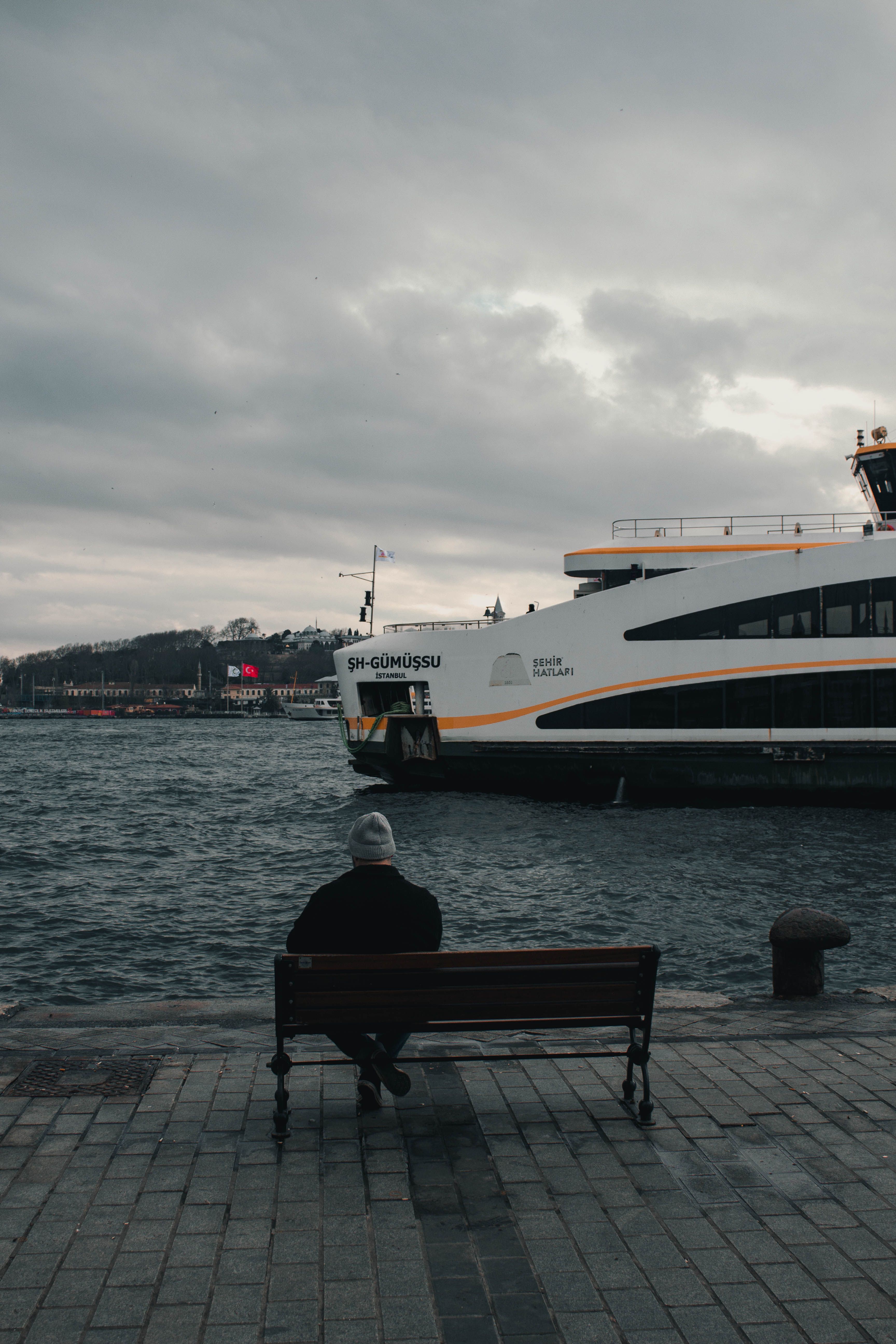 A man on a bench gazes at a ferry on the Bosphorus in Istanbul.