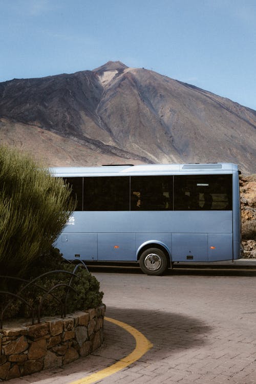 A blue bus is parked in front of a mountain