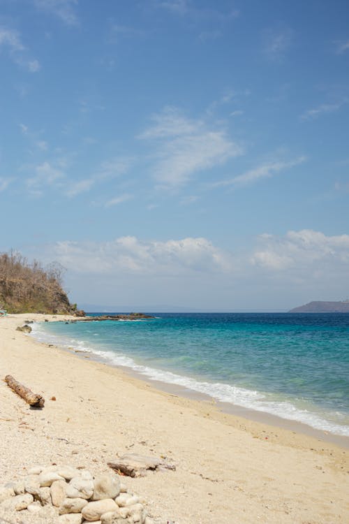 A sandy beach with a blue sky and water