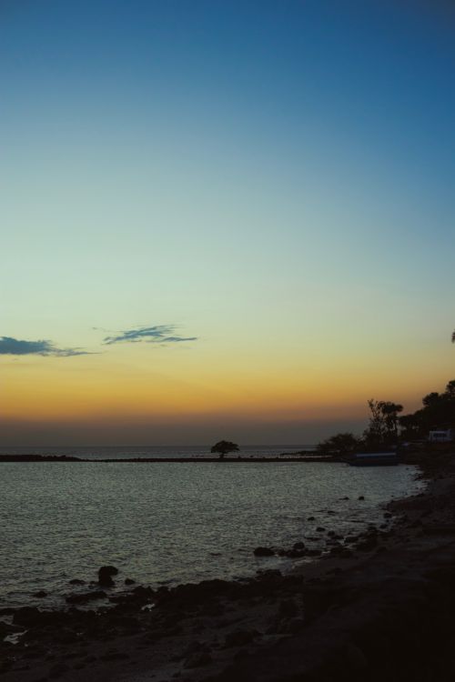 Free A tranquil coastline at sunset with a colorful sky and calm sea, capturing nature's beauty. Stock Photo