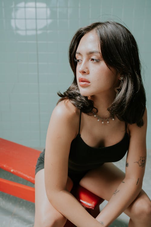 A woman sitting on a red bench in a bathroom